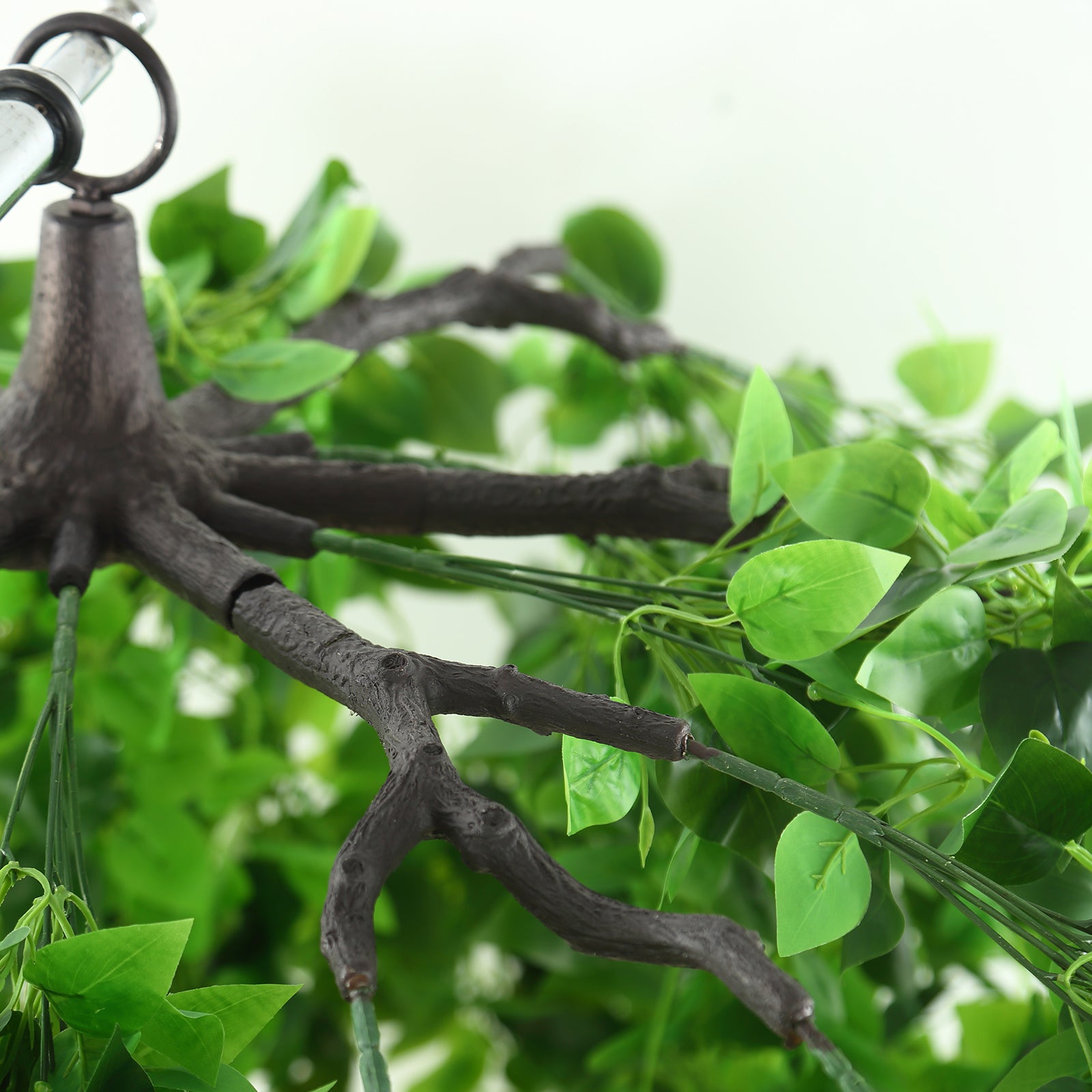 Green artificial eucalyptus leaf vines hanging from a chandelier.