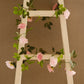 Blush dusty rose artificial silk flower garland on a wooden ladder.
