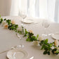Cream ivory artificial silk flower garland with mini rose vines on a table.