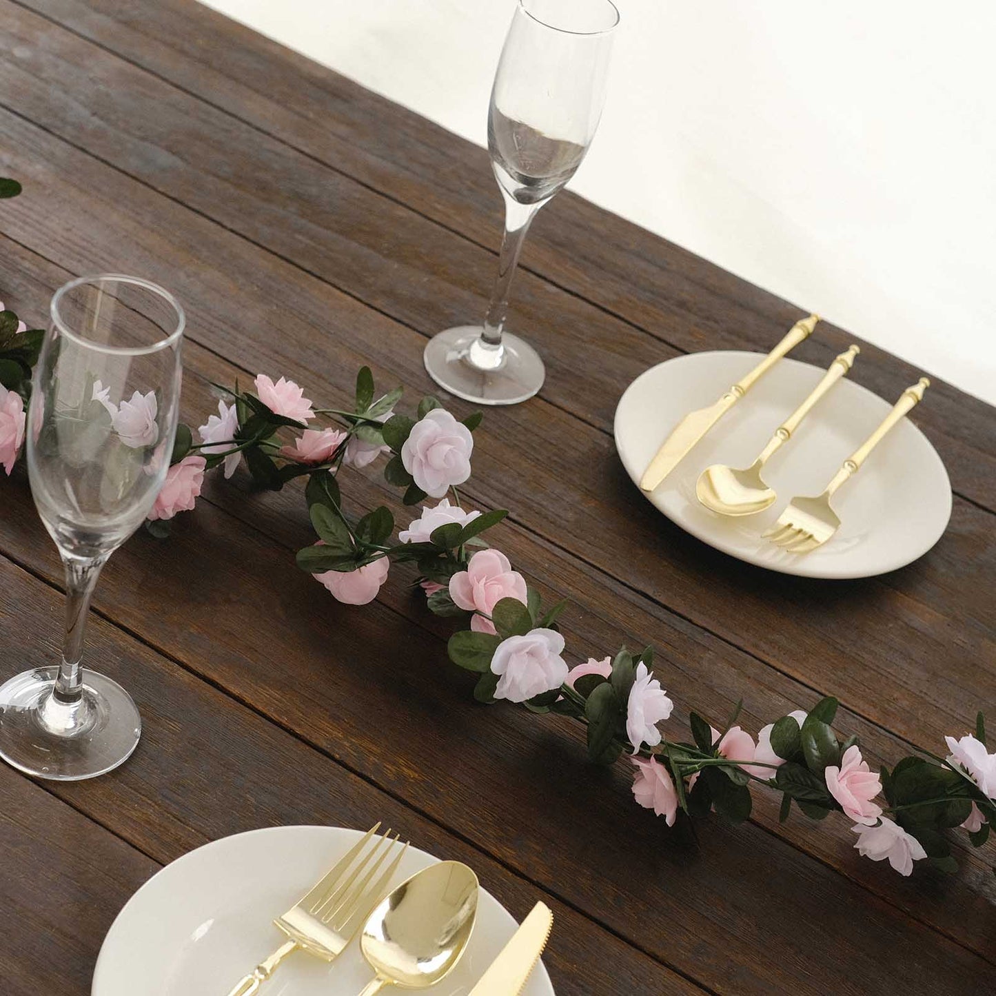 Blush dusty rose artificial silk flower garland with mini roses on a table setting.