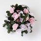 Blush pink artificial silk flower garland with green leaves.