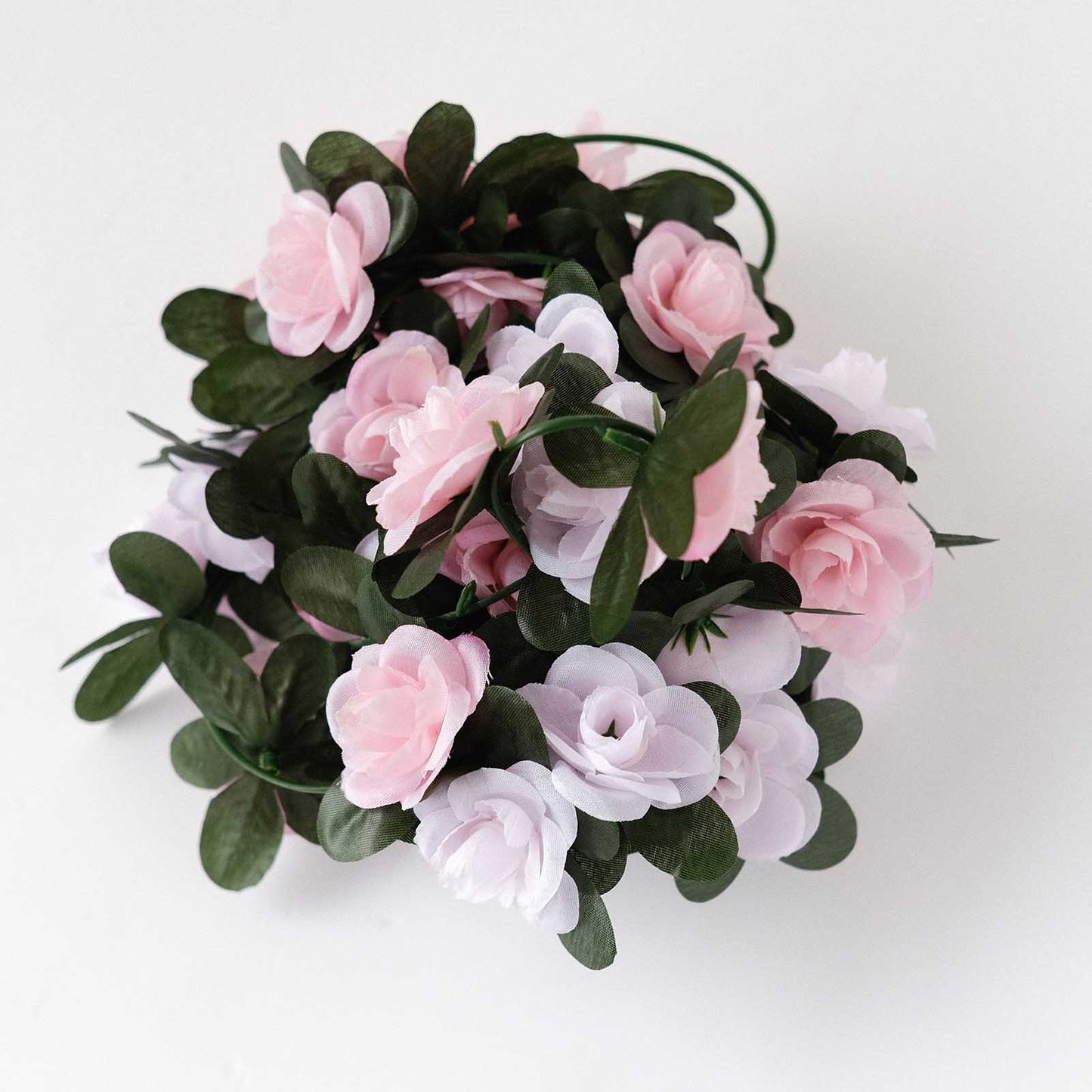 Blush pink artificial silk flower garland with green leaves.