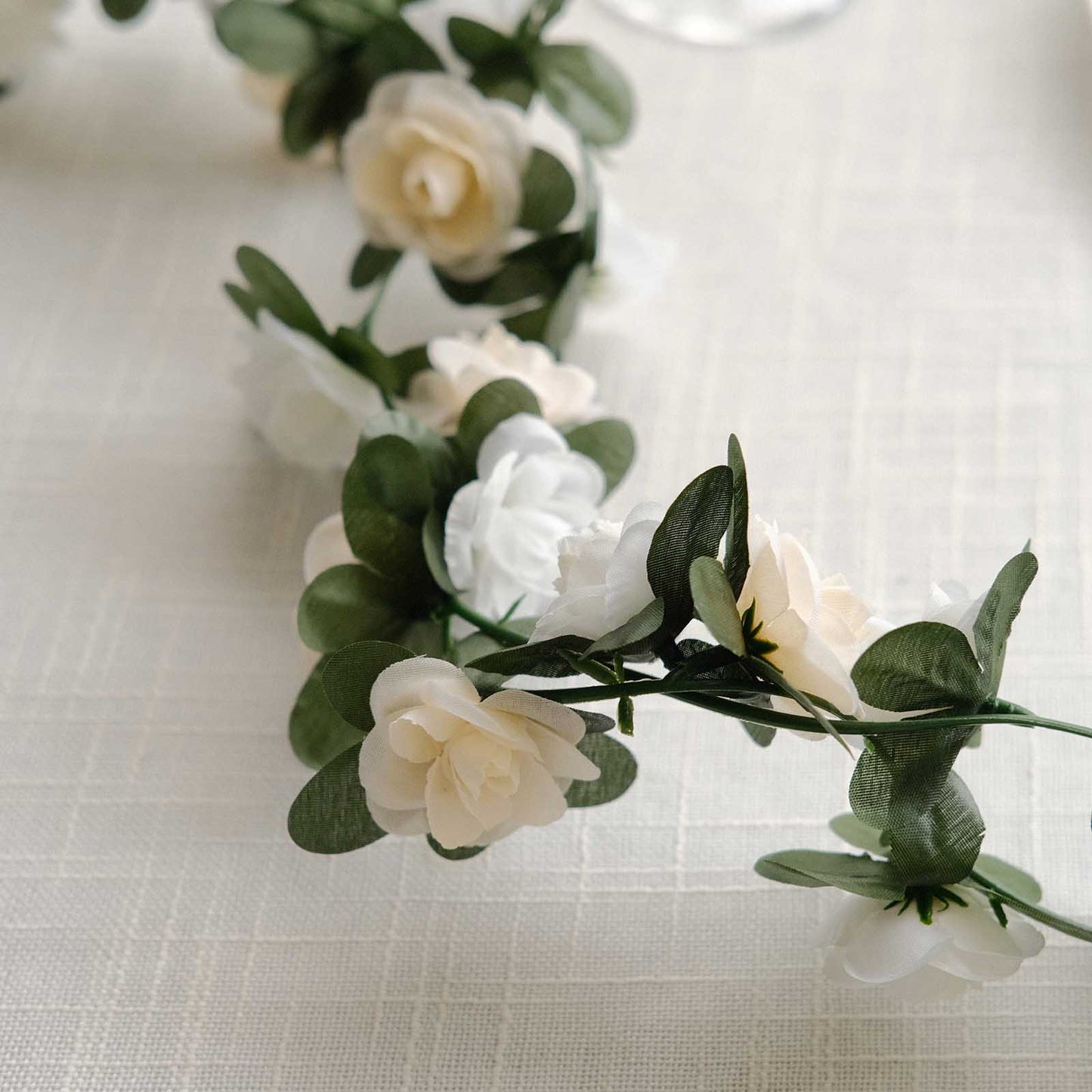 Cream ivory artificial silk flower garland with mini rose vines and green leaves.