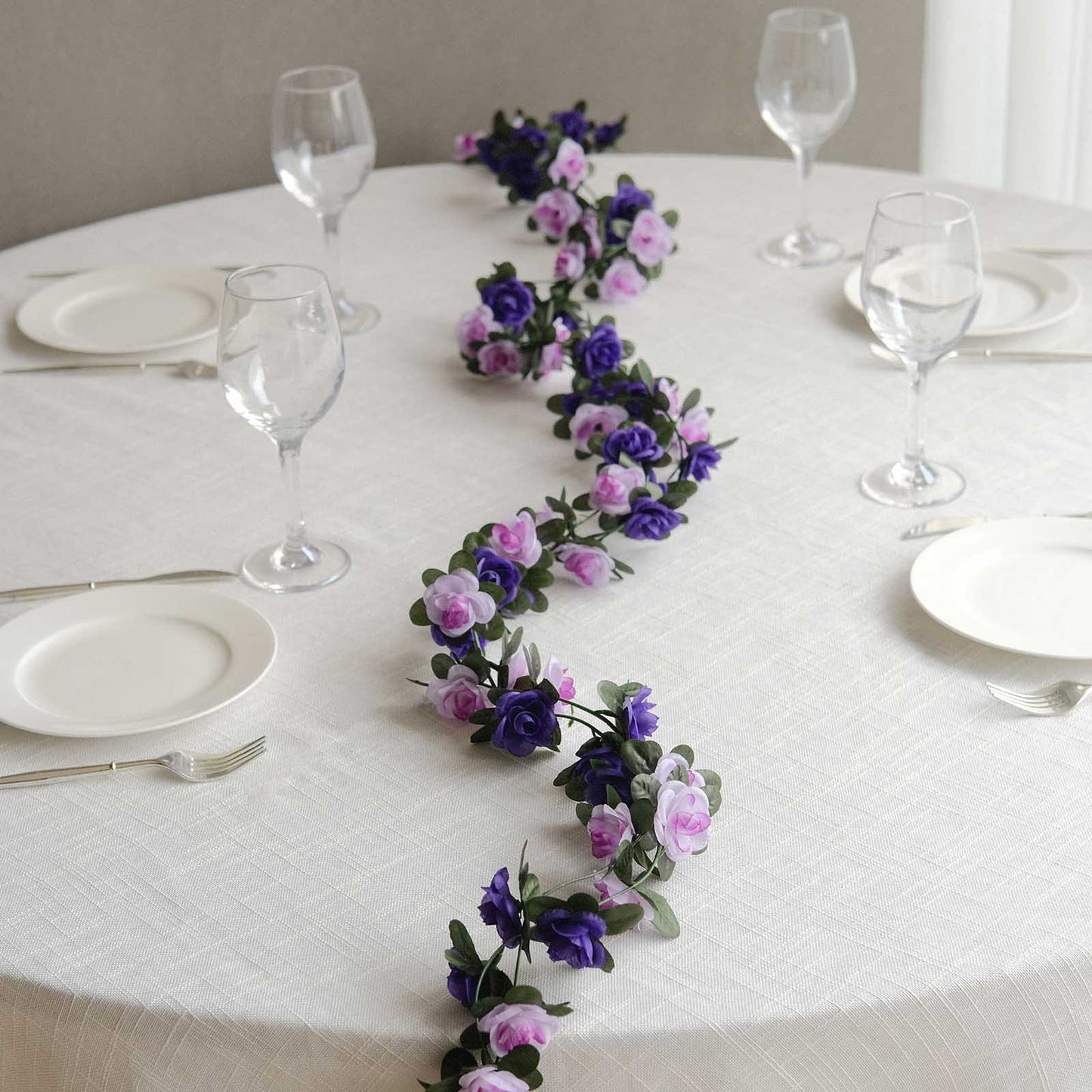 Lavender purple artificial silk flower garland with mini rose vines on a table.