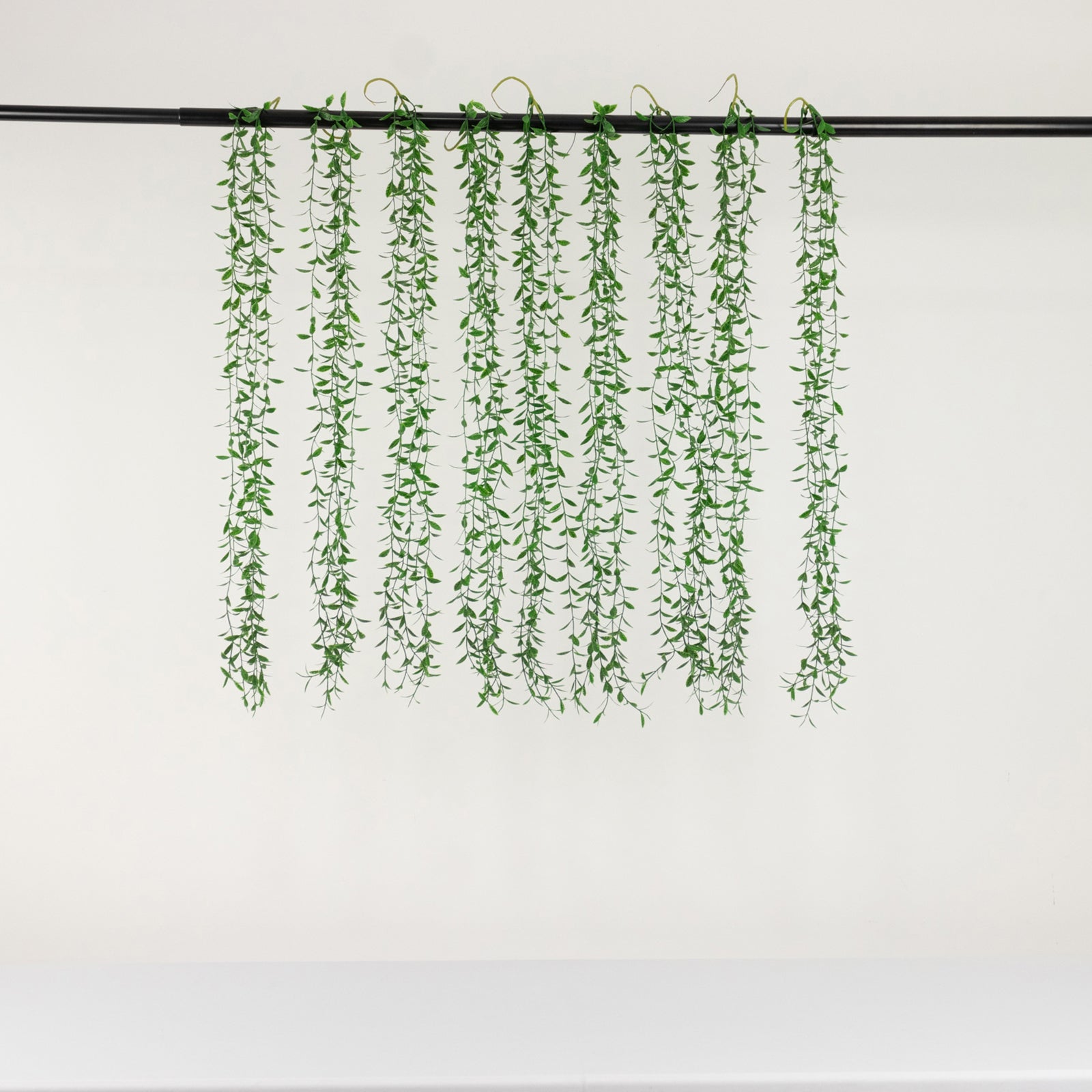 Green artificial hanging vines with weeping willow leaves for decor.
