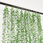 Green artificial hanging vines with weeping willow leaves for wall decor.