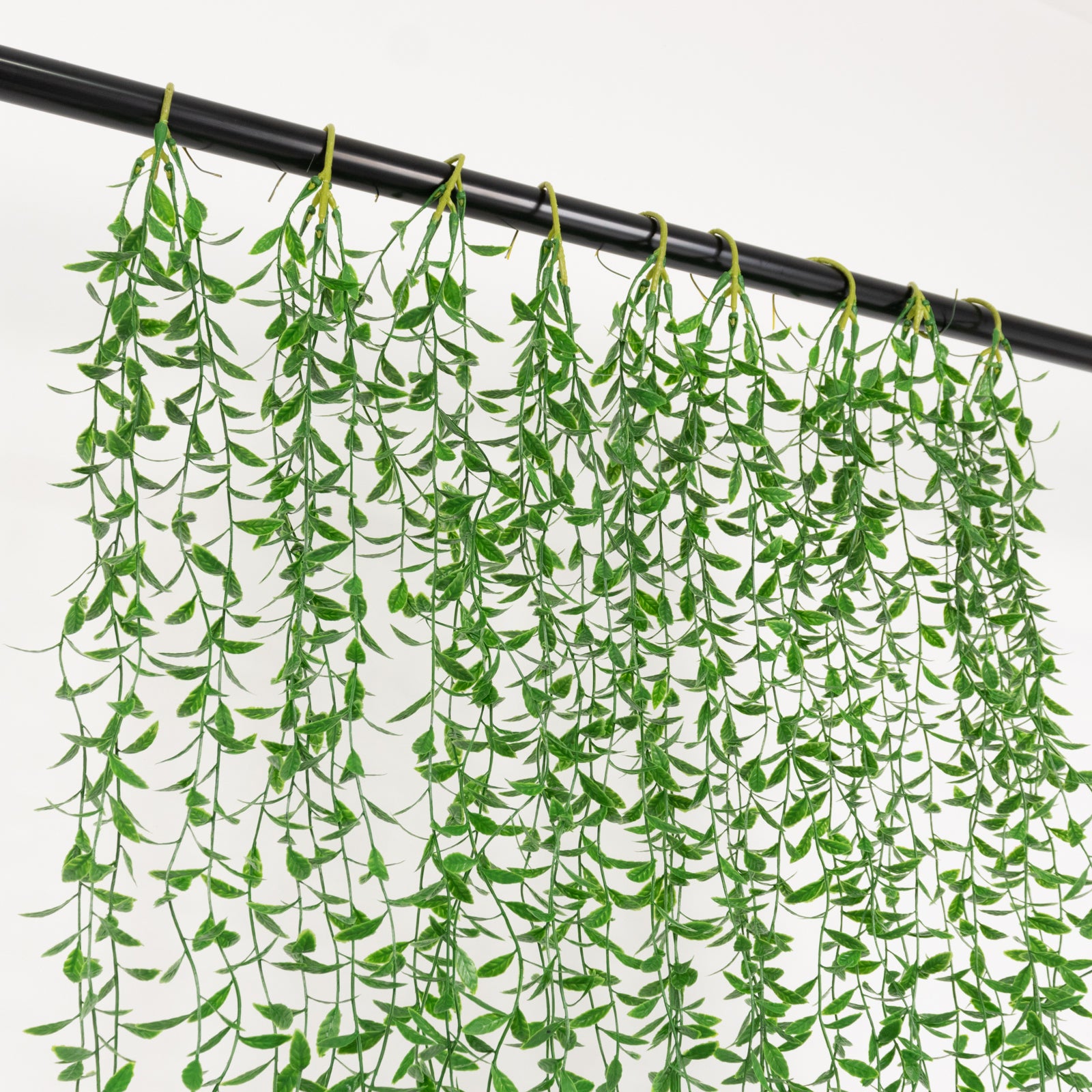 Green artificial hanging vines with weeping willow leaves for wall decor.