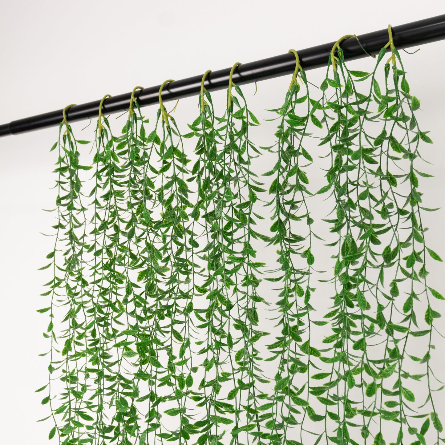 Green artificial hanging vines with weeping willow leaves for wall decor.