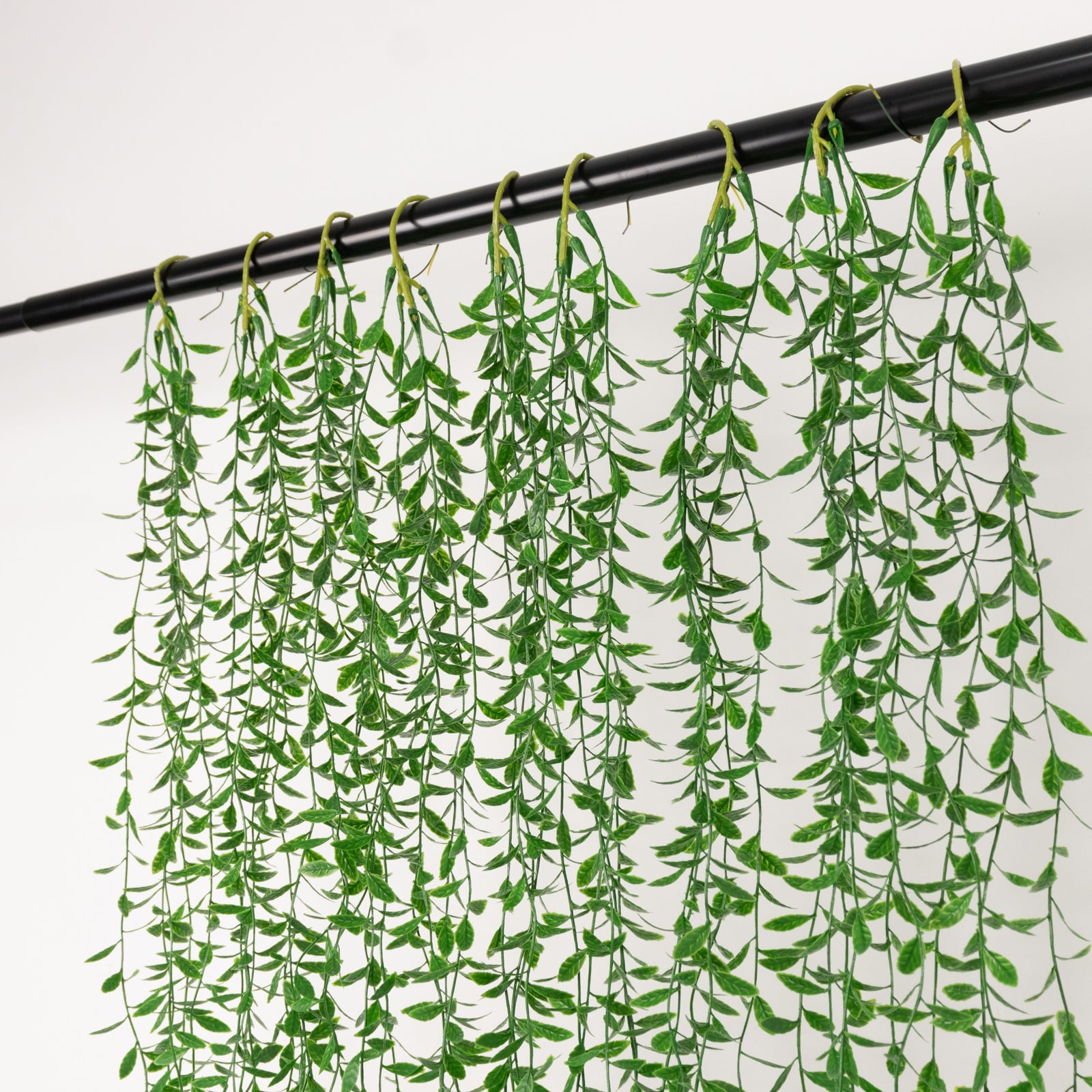 Green artificial hanging vines with weeping willow leaves for wall decor.