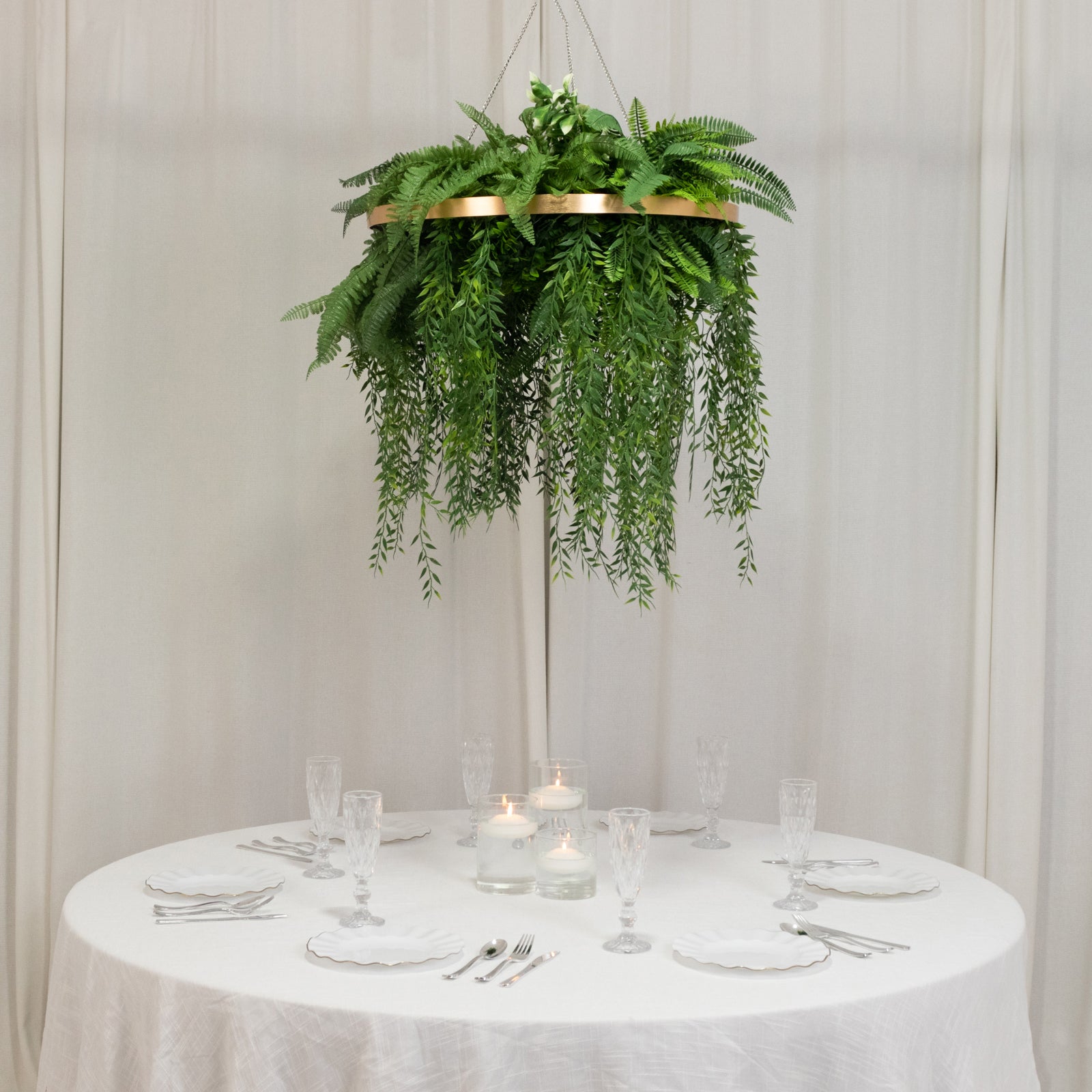 Large faux greenery hoop chandelier with draping ferns in gold.