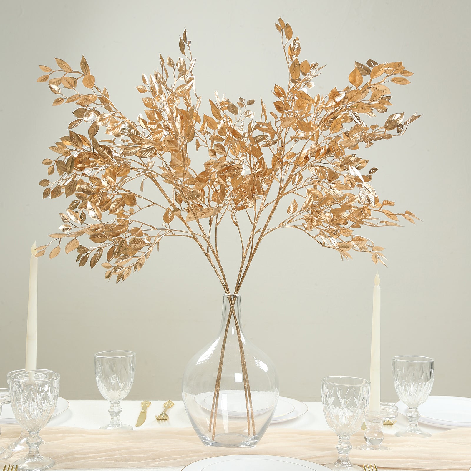 Gold metallic artificial leaf spray arrangement in a clear vase.
