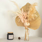 Blush dried pampas grass bouquet in a glass vase with a candle.