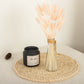 Blush dried pampas grass bouquet in a vase on a woven placemat.