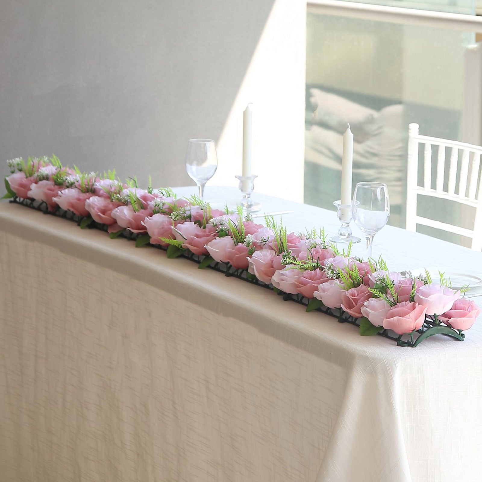 Dusty rose silk flower table runner with artificial floral arrangements.
