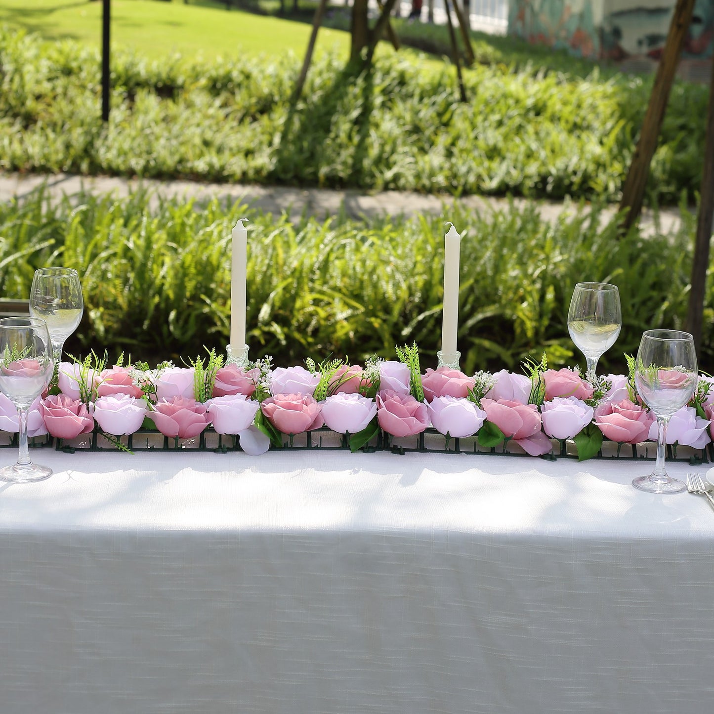 Dusty rose silk flower table runner with artificial floral arrangements.