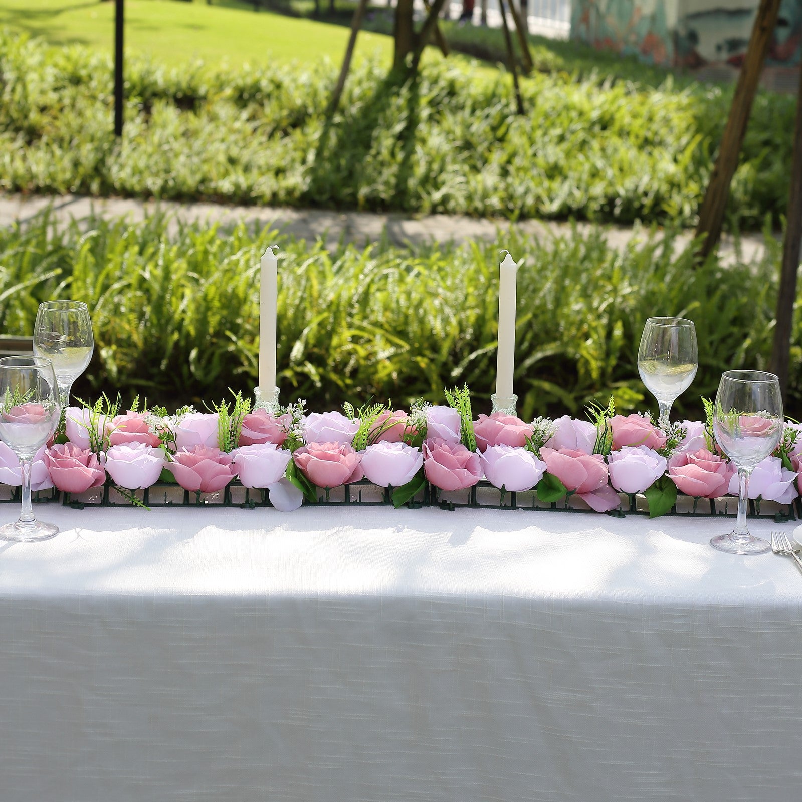 Dusty rose silk flower table runner with artificial floral arrangements.