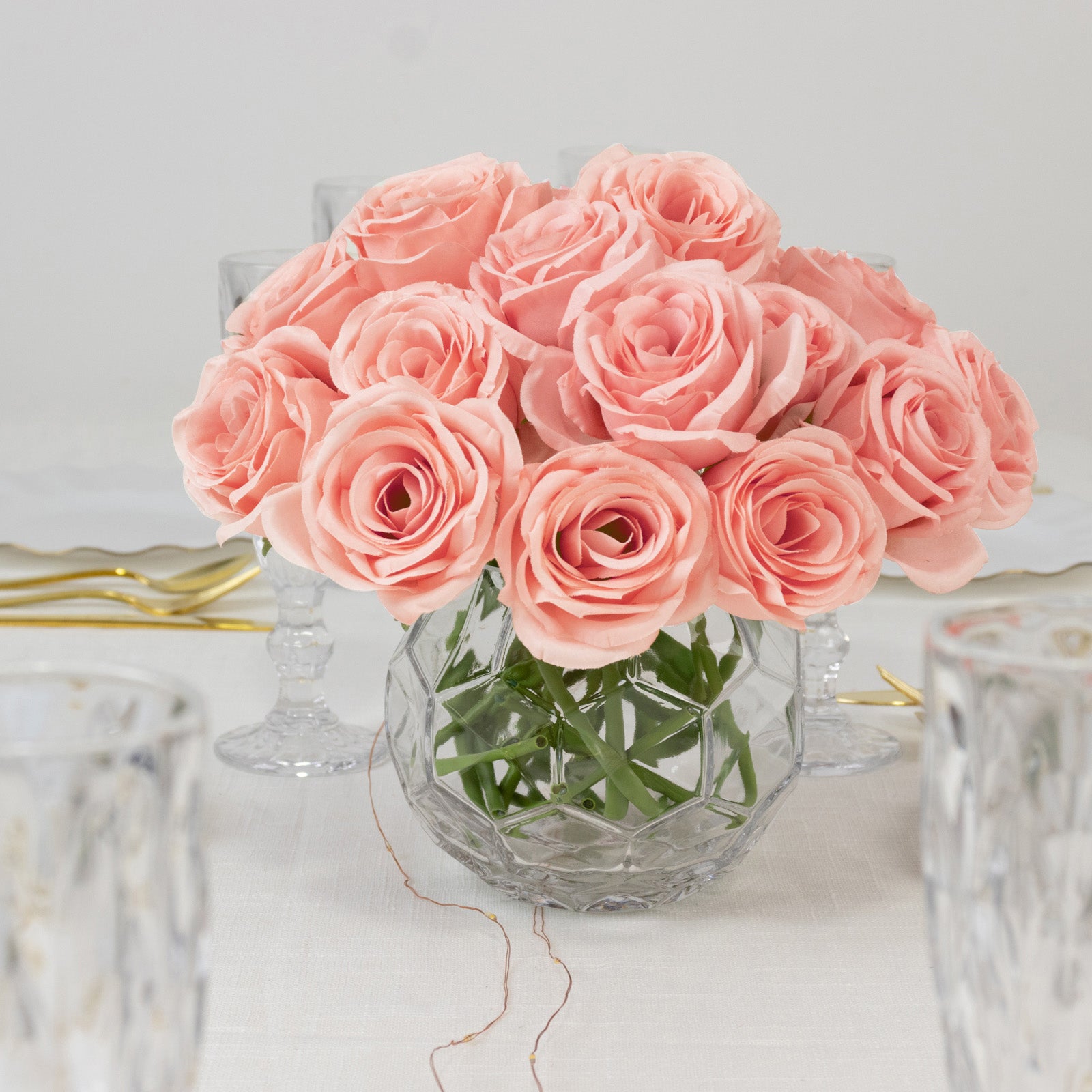 Pink artificial silk roses in a glass vase for elegant flower arrangements.