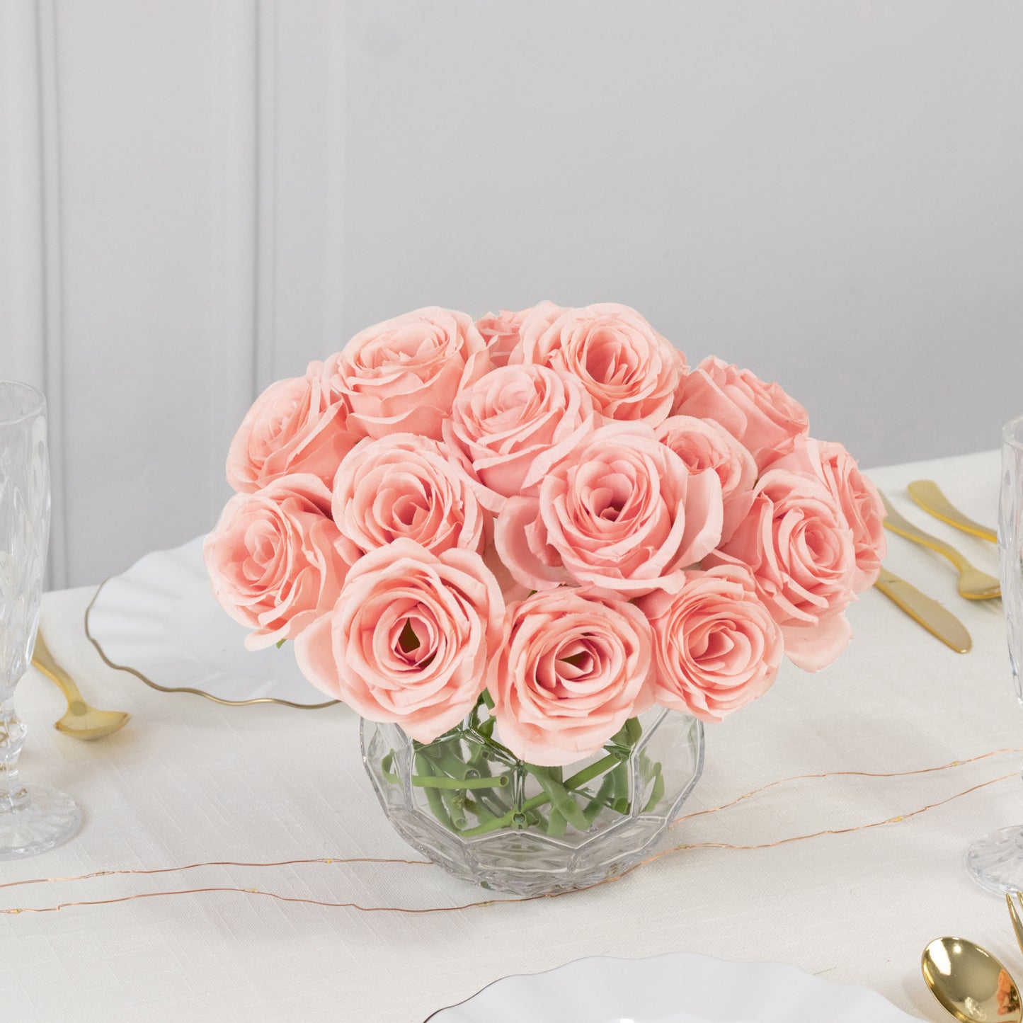 Pink artificial silk roses in a glass vase for floral arrangements.