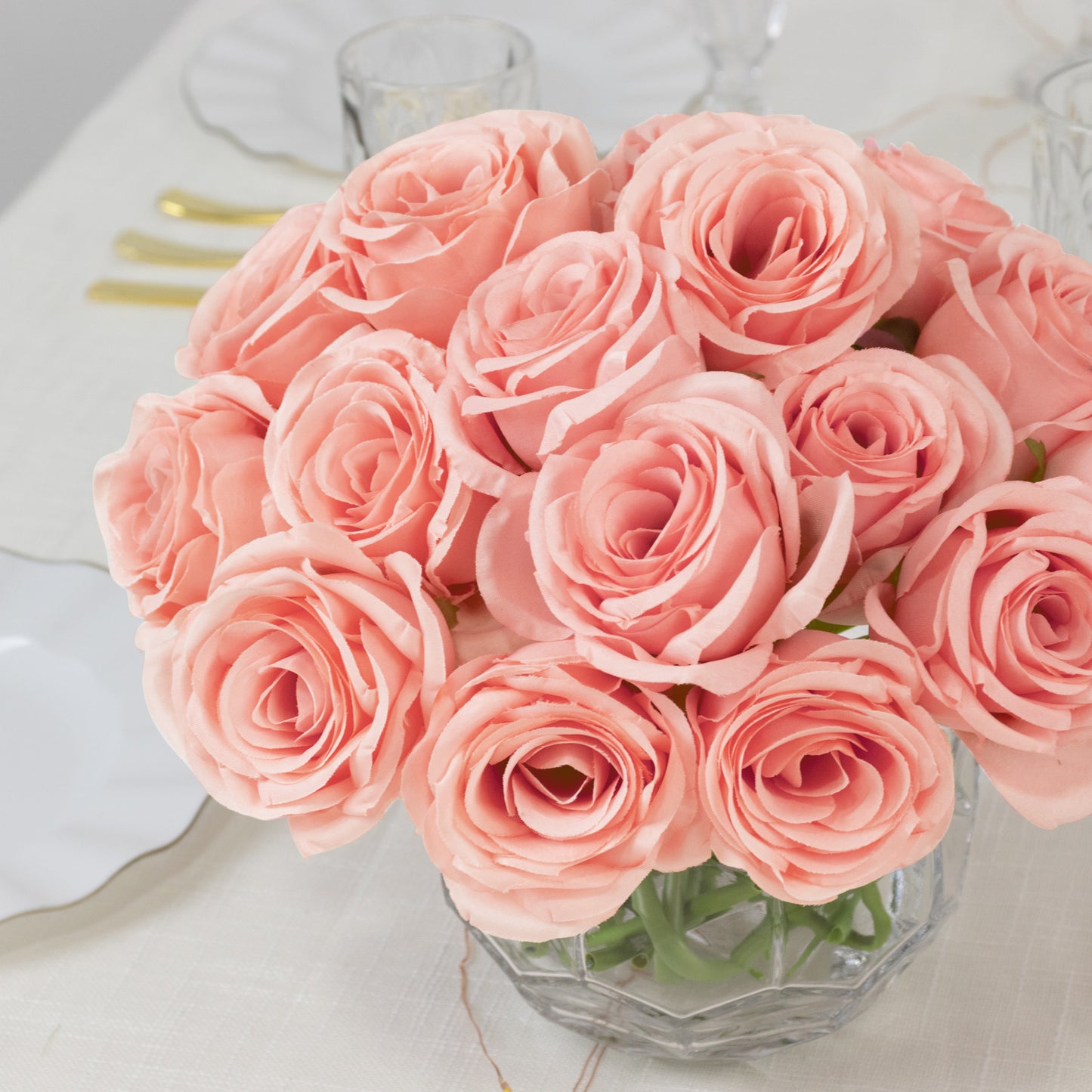 Pink artificial silk roses bouquet in a clear glass vase.
