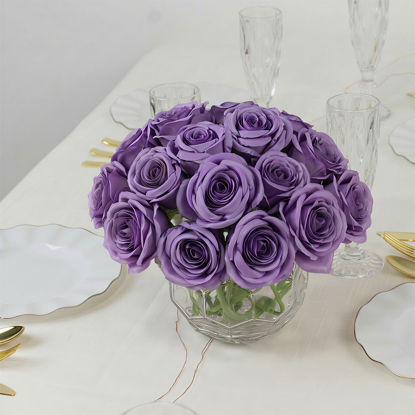 Purple artificial silk roses bouquet in a clear glass vase.
