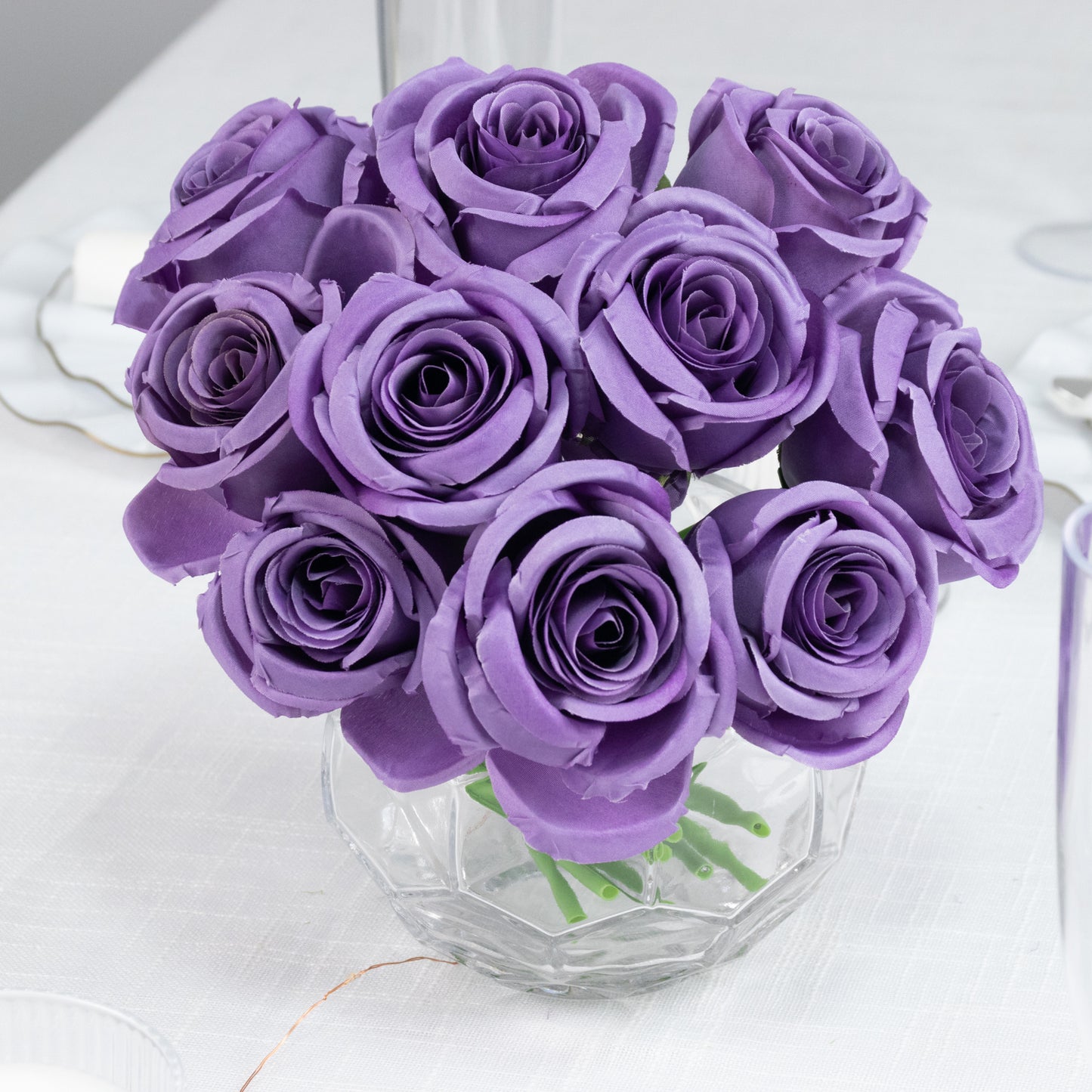 Purple artificial silk roses in a bouquet arrangement.