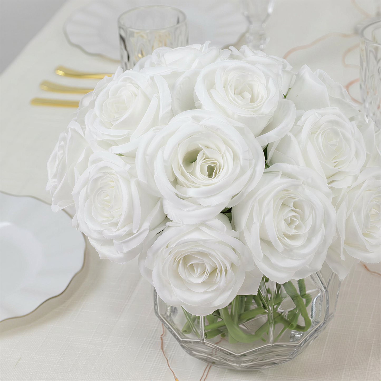 White artificial silk roses bouquet in a clear glass vase.