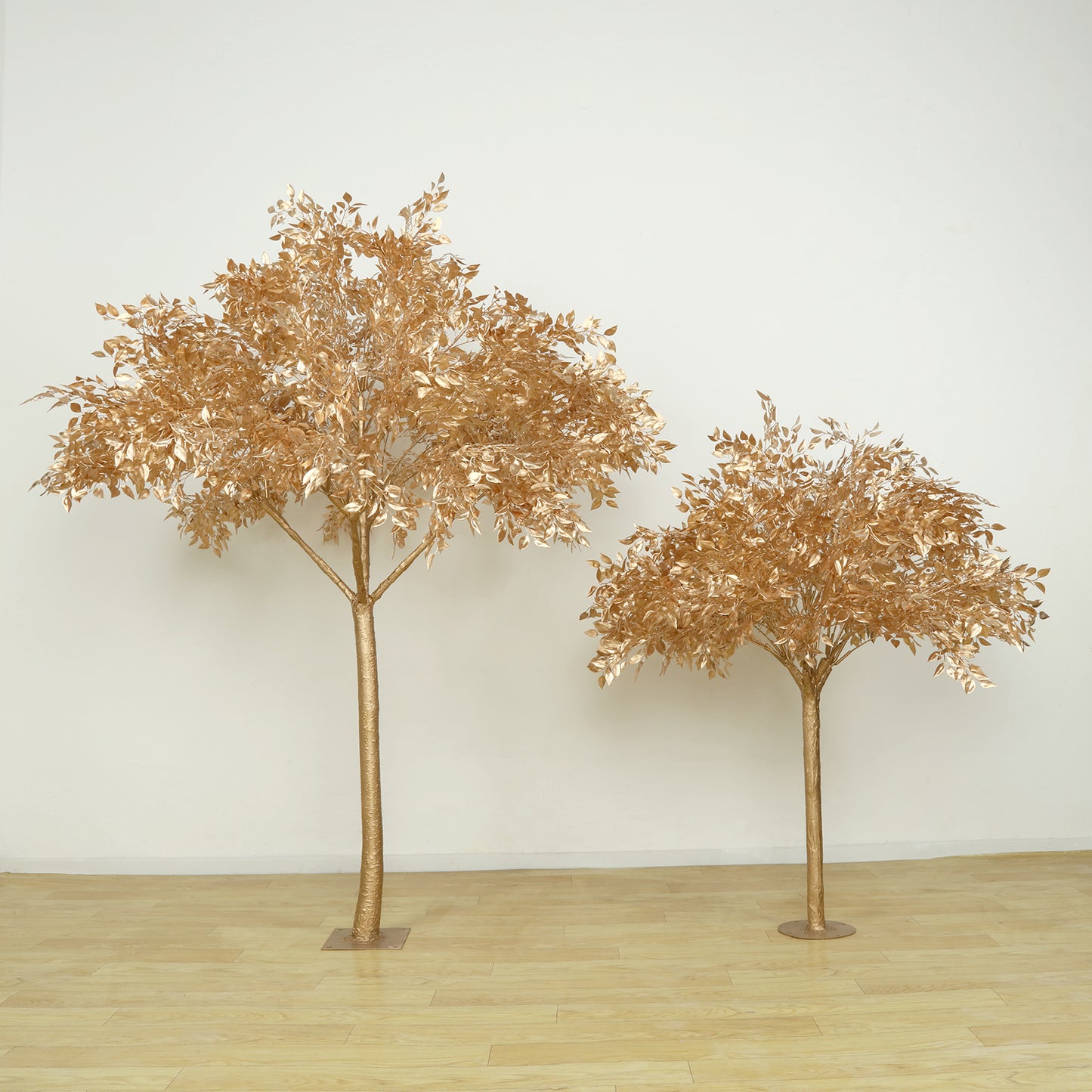 Golden faux leaf trees with natural-look trunks for floor decor.