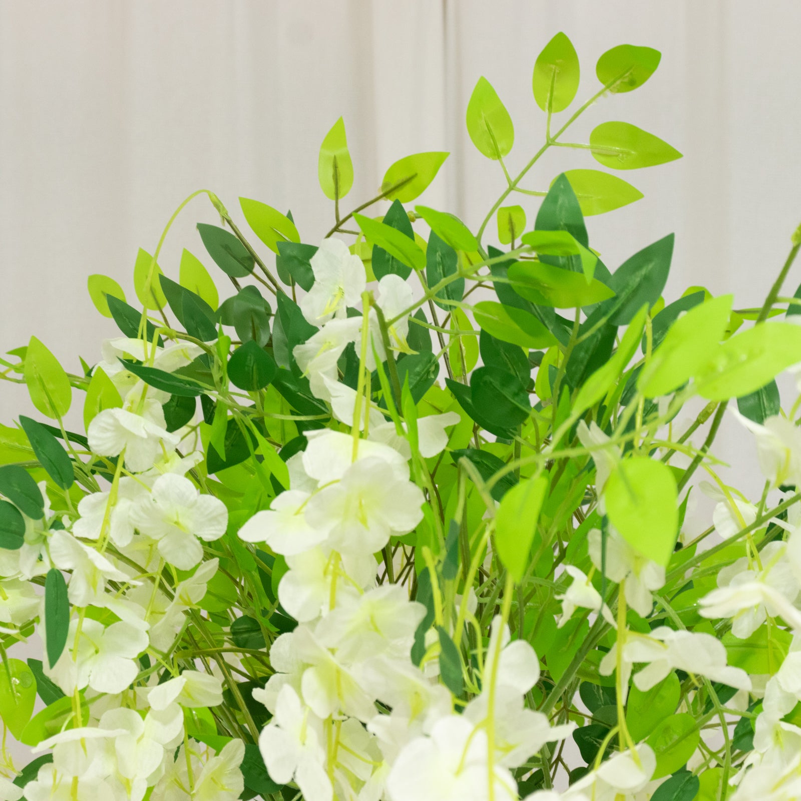 Cream artificial wisteria tree with cascading silk flowers and natural trunk.