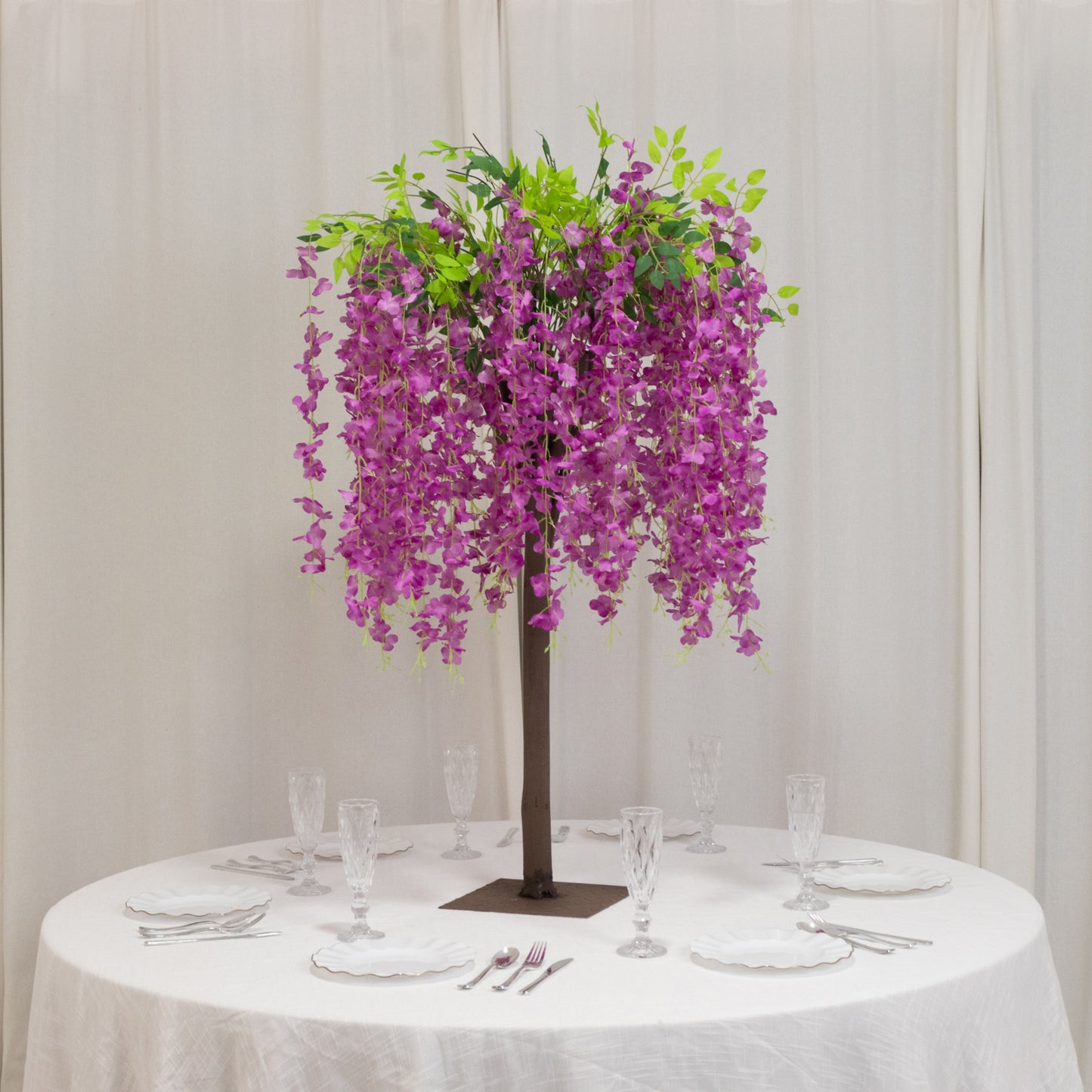 Lavender lilac artificial wisteria tree with cascading silk flowers on a table.