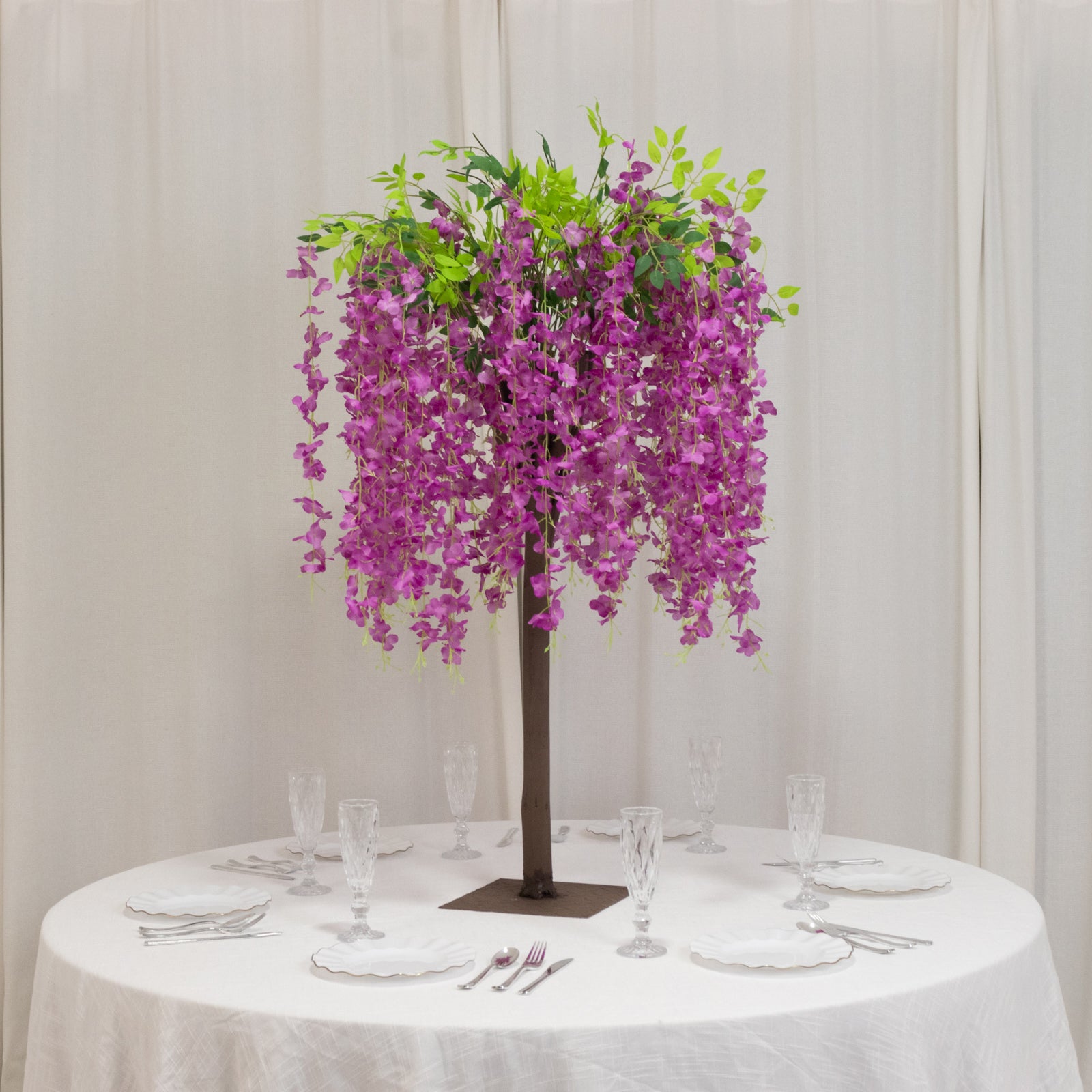 Lavender lilac artificial wisteria tree with cascading silk flowers on a table.