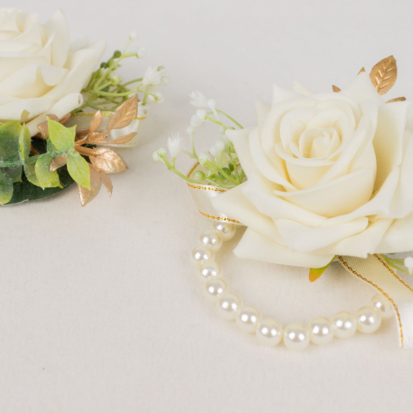 White artificial rose wrist corsages with pearls for weddings.