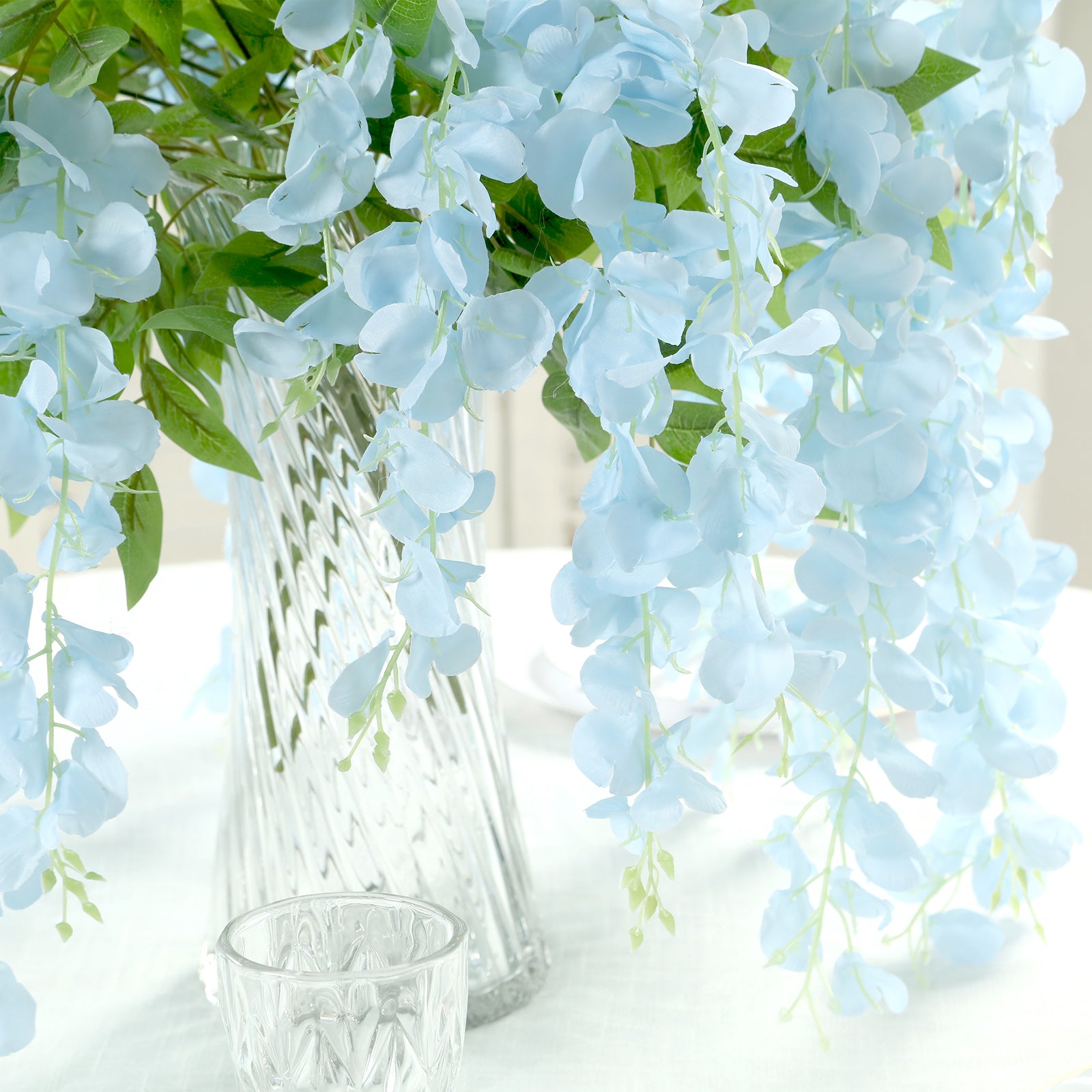 Light blue silk wisteria flower garland vines in a clear vase.