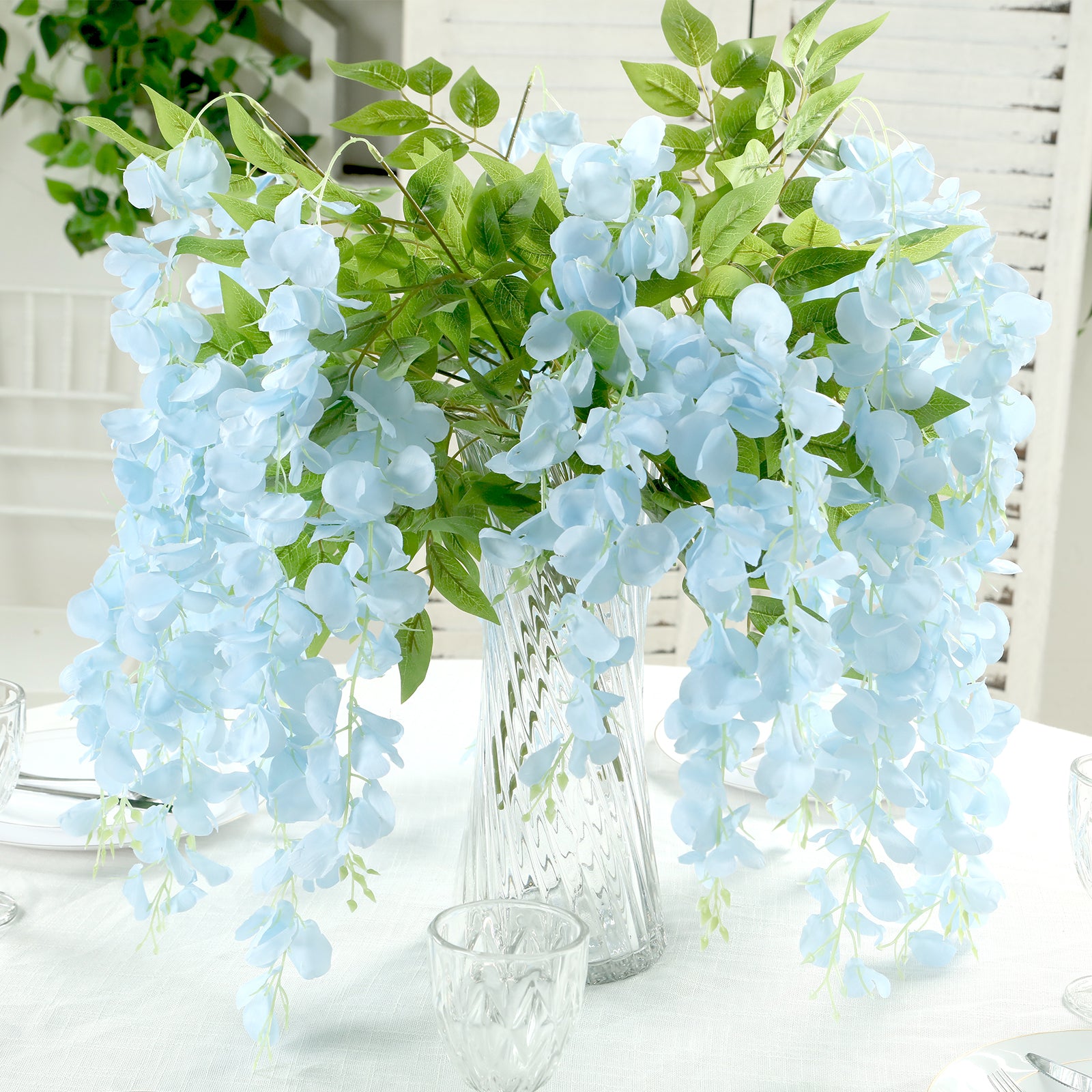 Light blue silk hanging wisteria flower garland in a decorative vase.