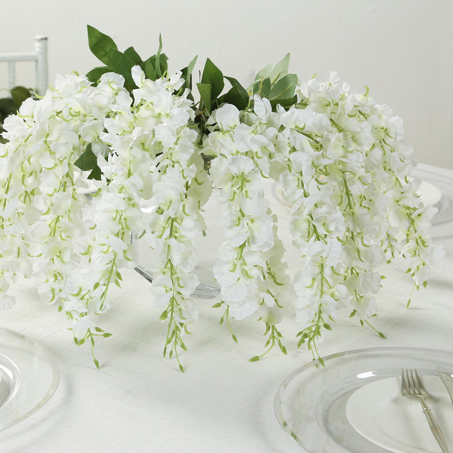 White cream silk wisteria vines hanging plants, elegant floral centerpiece.