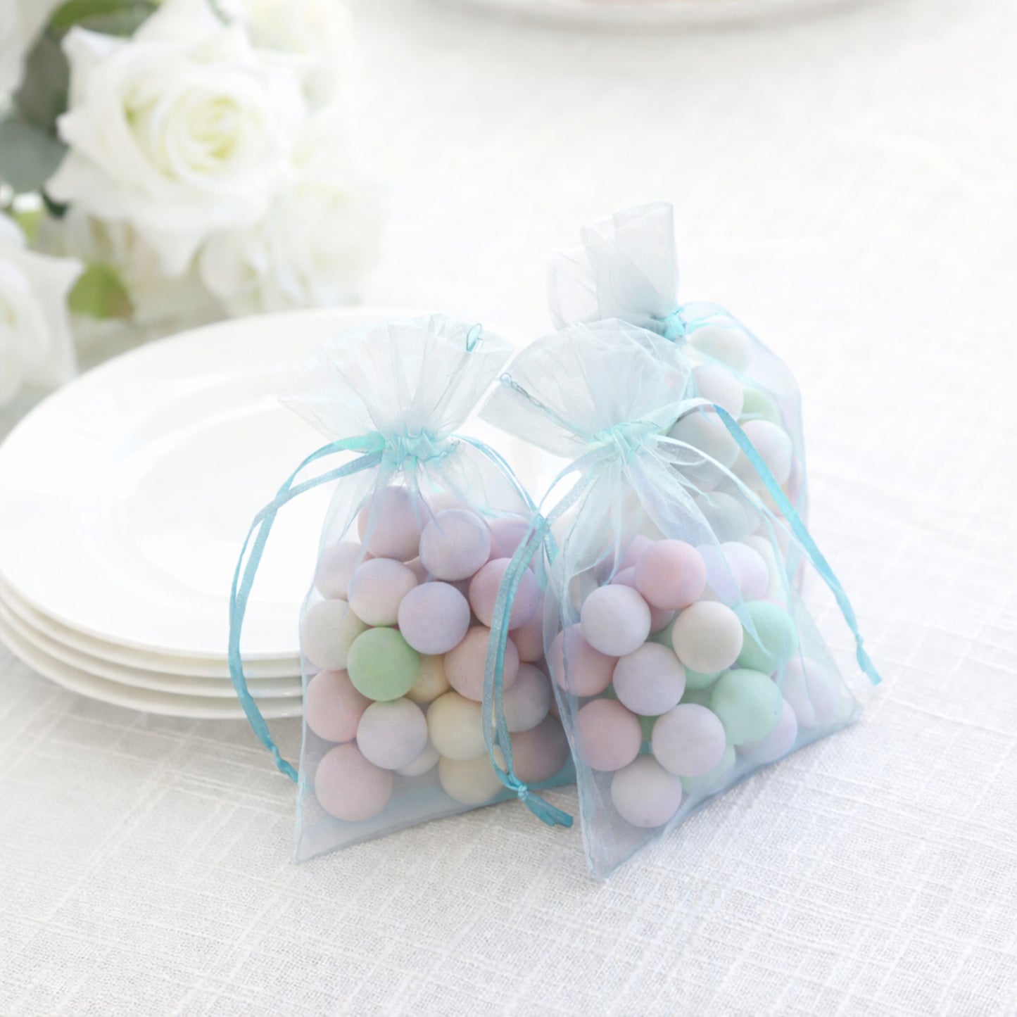 Light blue organza gift bags filled with colorful candies.
