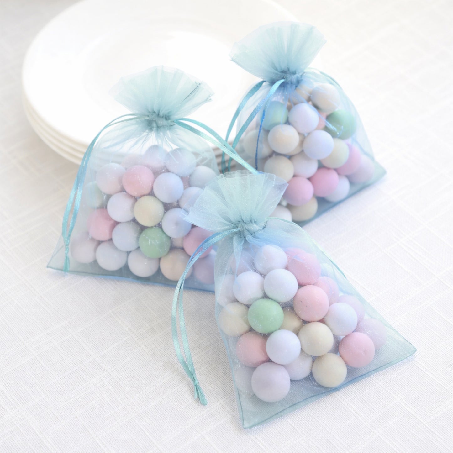 Light blue organza gift bags filled with colorful candies.