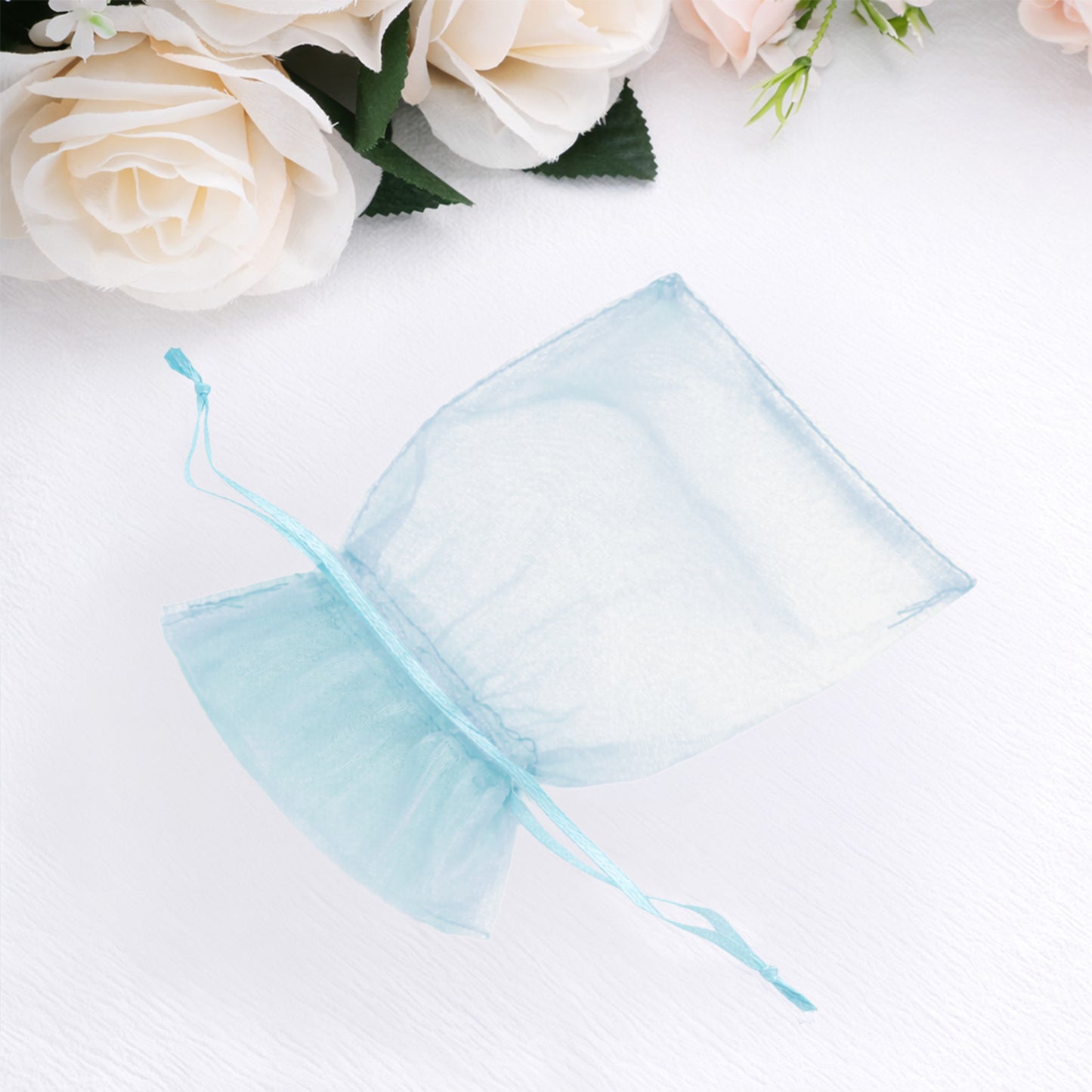 Light blue organza gift bag with drawstring, perfect for wedding favors.