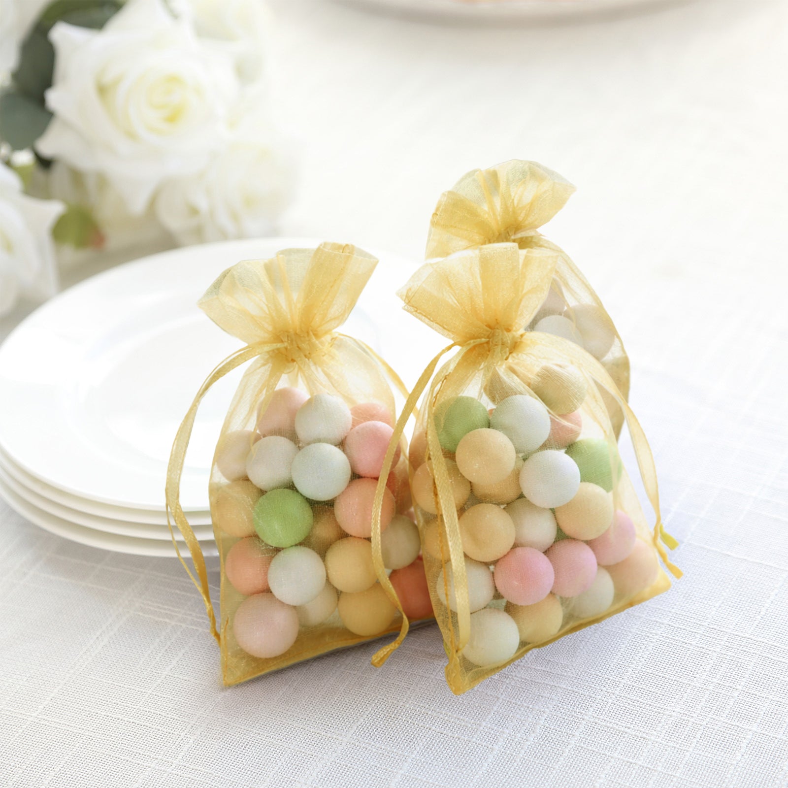Gold organza gift bags filled with colorful candies. Perfect for wedding favors.