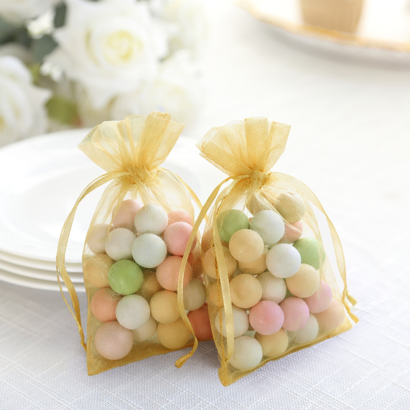 Gold organza gift bags with drawstring, filled with colorful round candies.