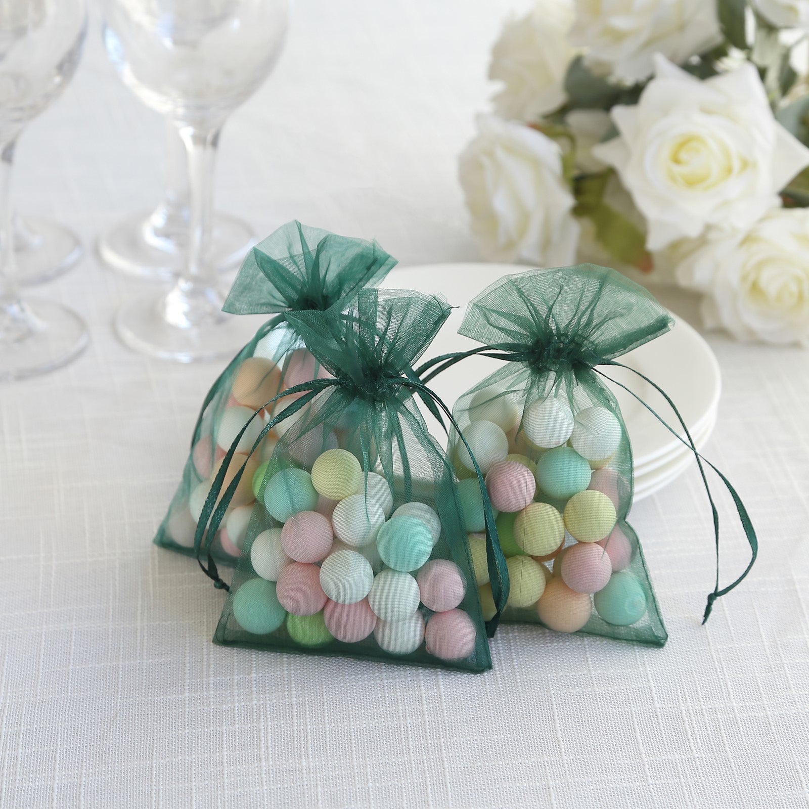 Emerald green organza gift bags with drawstring for weddings and parties.