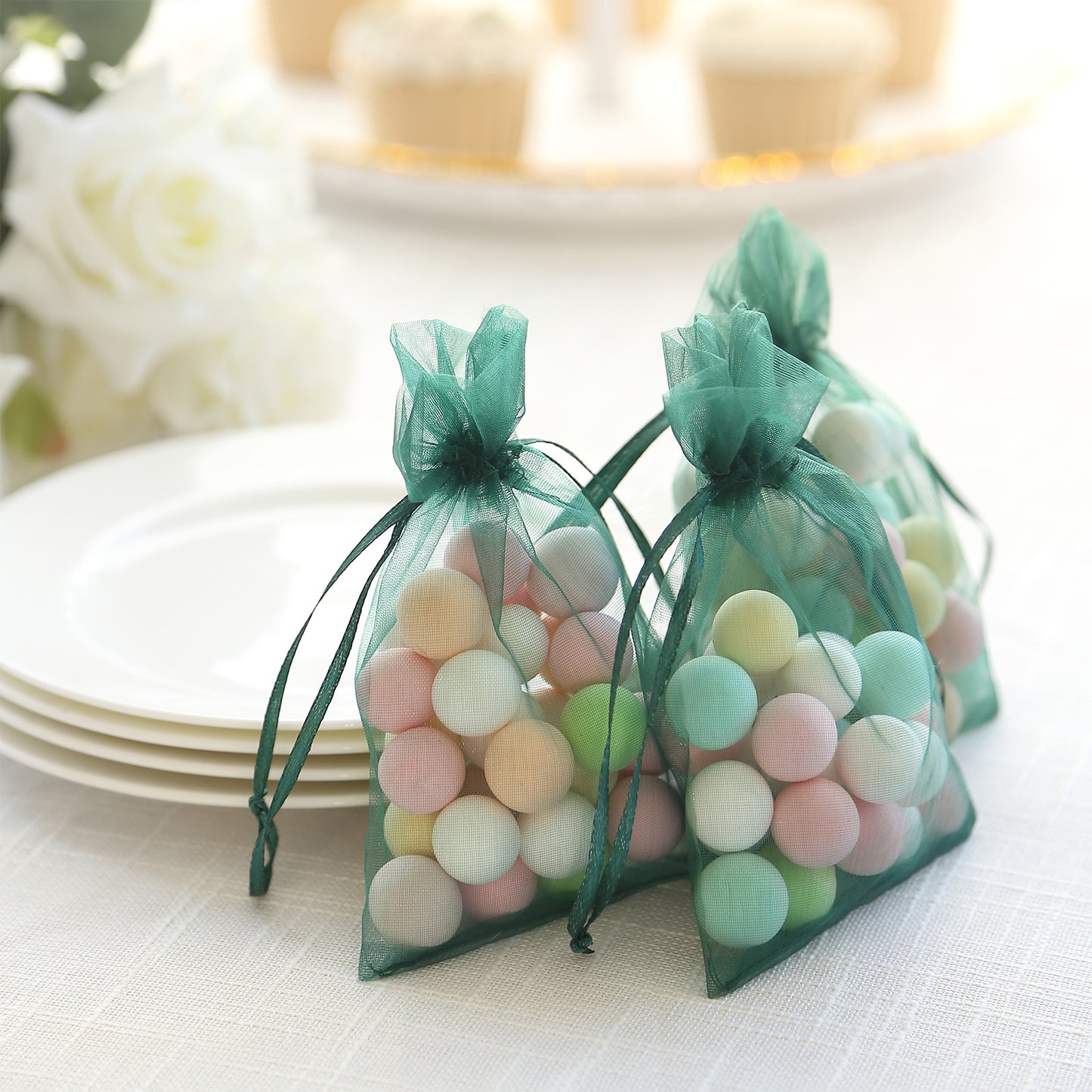 Hunter emerald green organza gift bags with drawstring, filled with colorful candies.
