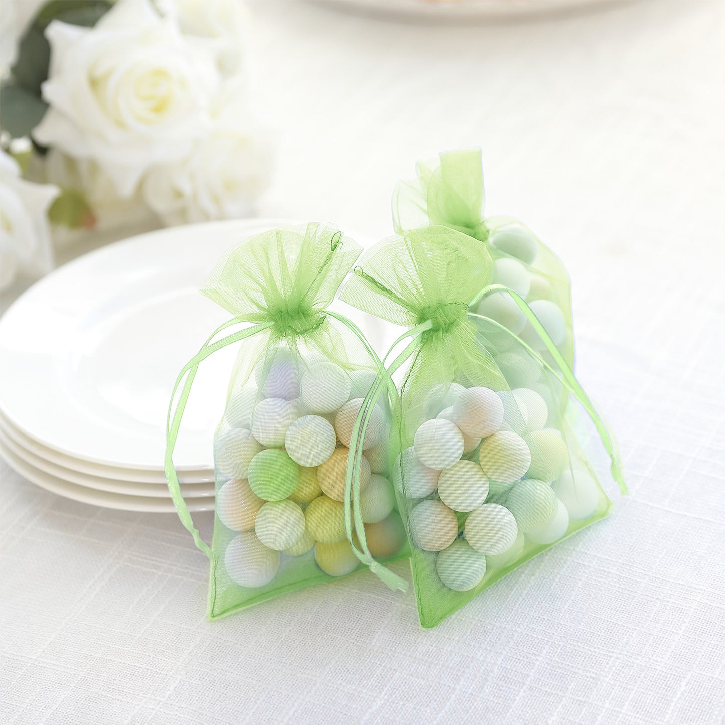 Green organza gift bags with drawstring, filled with colorful decorative balls.