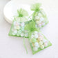 Mint organza gift bags with drawstring, filled with pastel balls.
