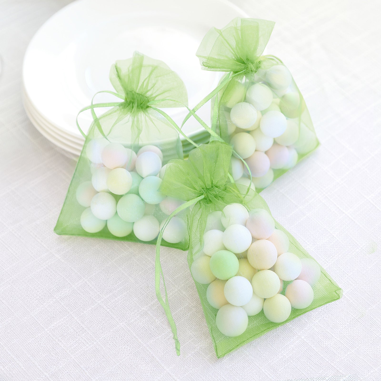 Mint organza gift bags with drawstring, filled with pastel balls.