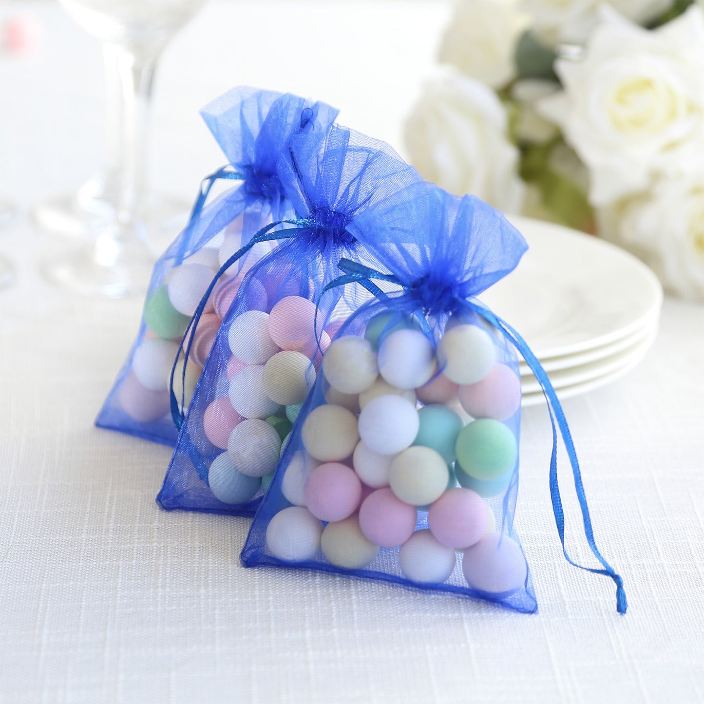 Royal blue organza gift bags with drawstring, filled with colorful candies.