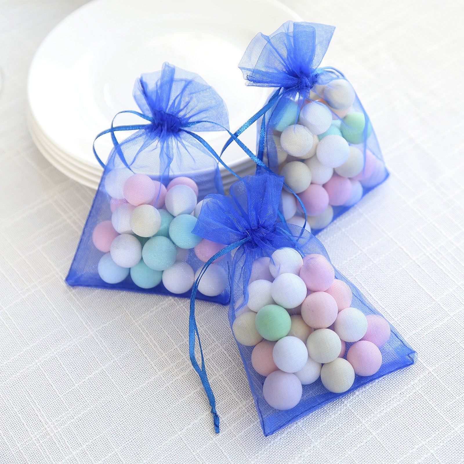Royal blue organza gift bags with drawstring, filled with colorful candies.