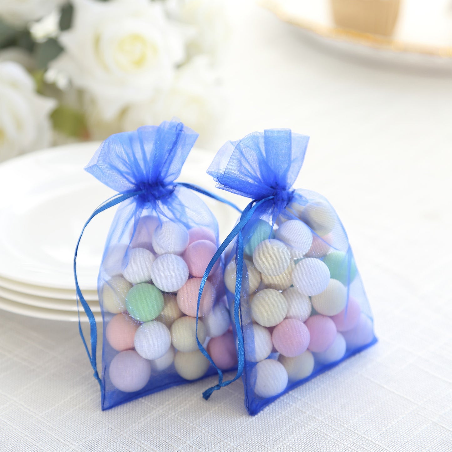 Royal blue organza gift bags with drawstring, filled with colorful treats.