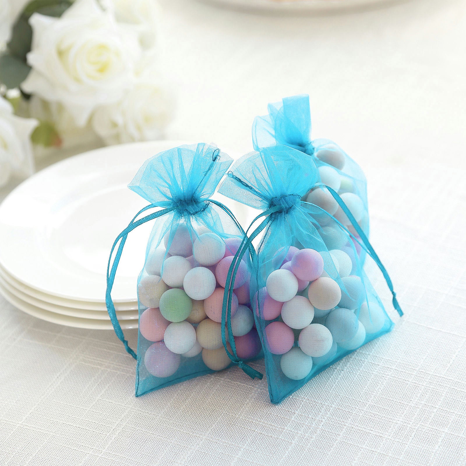 Turquoise organza gift bags with drawstring, perfect for wedding favors.