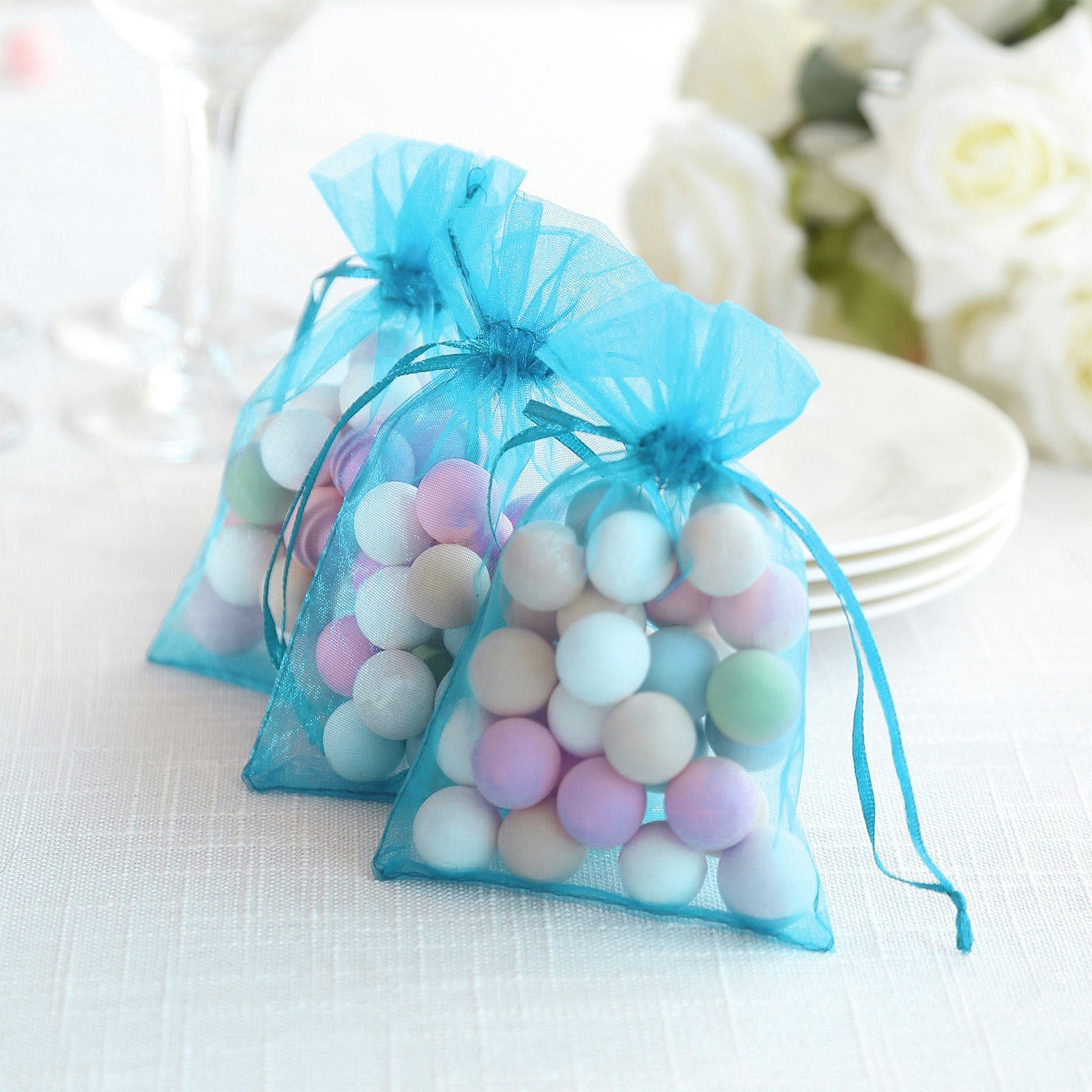 Turquoise organza gift bags with drawstring, perfect for wedding favors.