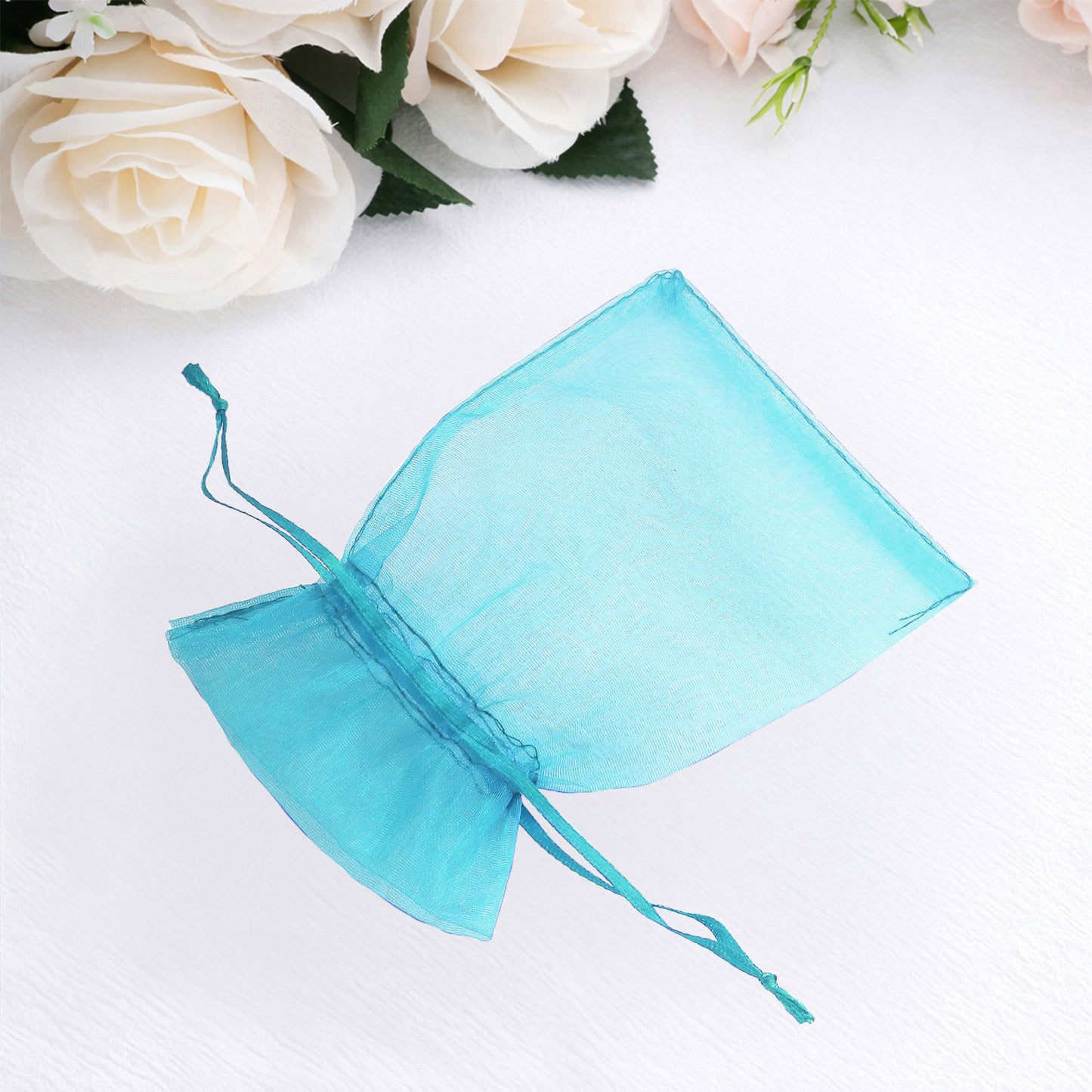 Turquoise organza gift bag with drawstring, ideal for wedding favors.
